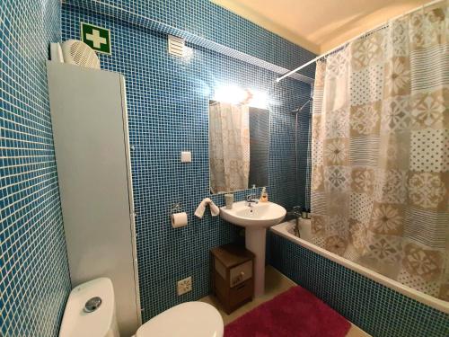 Baño de azulejos azules con aseo y lavamanos en Apartment Amalia, en Albufeira