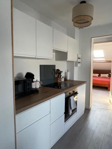 une cuisine avec des placards blancs et un comptoir marron dans l'établissement l'Ambre de Calais - Elégance et plénitude, à Calais