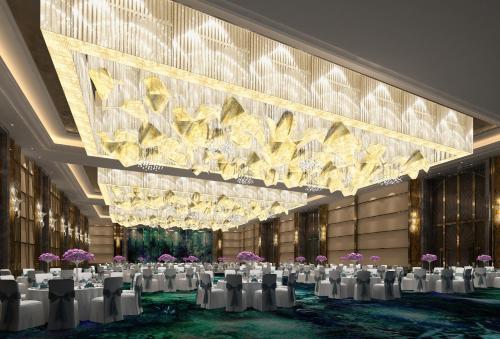 a banquet hall with white chairs and a large chandelier at Wanda Vista Nanning in Nanning