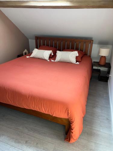 a bedroom with a bed with orange sheets and white pillows at l'Ambre de Calais - Elégance et plénitude in Calais