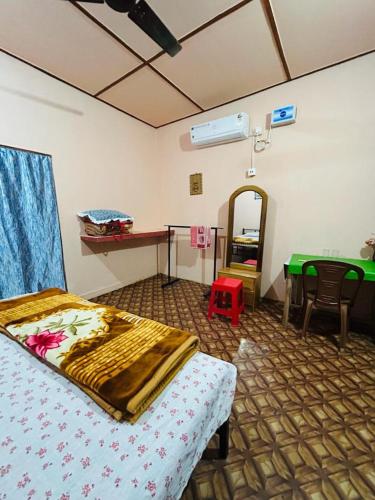 a bedroom with a bed and a desk and a table at Orchid Park Homestay in Sivasagar