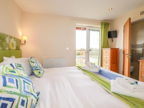 a bedroom with a large white bed with a window at 207 The Glades - Retallack Resort and Spa in Saint Columb Major