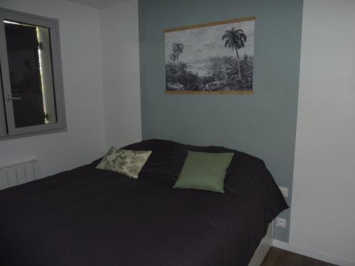 a bedroom with a black bed with a picture on the wall at Houlgate in Houlgate