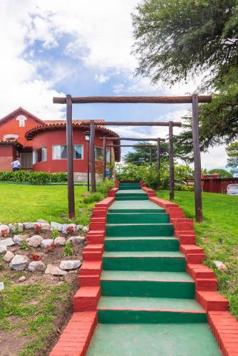 a pathway with green and red stones and a house at Castelar - Hotel & Apart in Huerta Grande