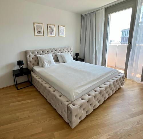 a large bed in a bedroom with a large window at The View 15.06 Quartier Belvedere in Vienna