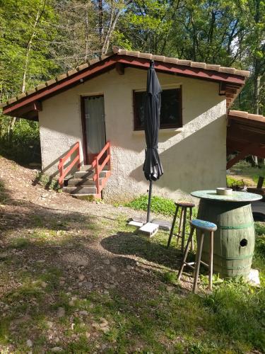 une petite maison avec un parasol et une table dans l'établissement L'Aire du paon, à Aire-sur-lʼAdour
