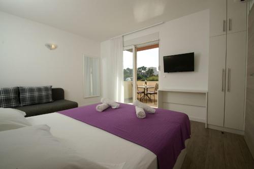 ein Schlafzimmer mit einem großen Bett mit einer lila Decke in der Unterkunft Apartmani Villa Dijana-Promajna in Promajna