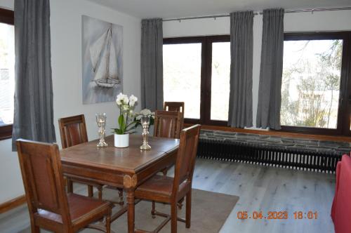 een eetkamer met een tafel, stoelen en ramen bij Dolomitenblick in Gerolstein