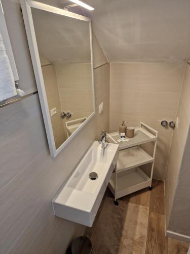 La salle de bains blanche est pourvue d'un lavabo et d'un miroir. dans l'établissement FLORA HOUSE, à La Spezia