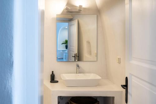 a bathroom with a white sink and a mirror at Karpimo Scenery in Firostefani