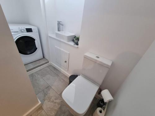 a bathroom with a toilet and a washing machine at South Terrace Apartment by Cliftonvalley Apartments in Weston-super-Mare