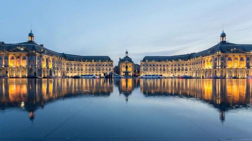 a large building with its reflection in the water at Clos Marcamps - Teritoria in Prignac-et-Marcamps