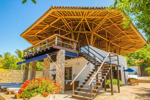 a building with a wooden roof and a staircase at Hotel Agua Baru by Mustique in Baru