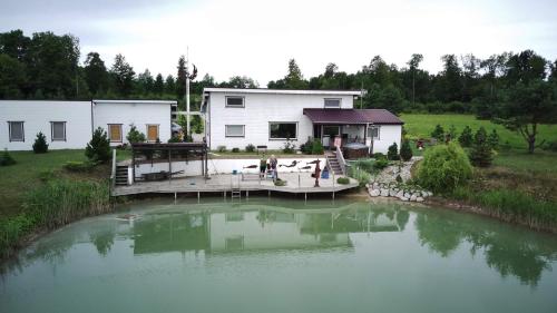 a house with a pond in front of it at Villa Feniksas in Poškai