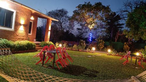 a garden with red chairs on the grass at night at The Royal Ascot Holiday Home in Alibaug