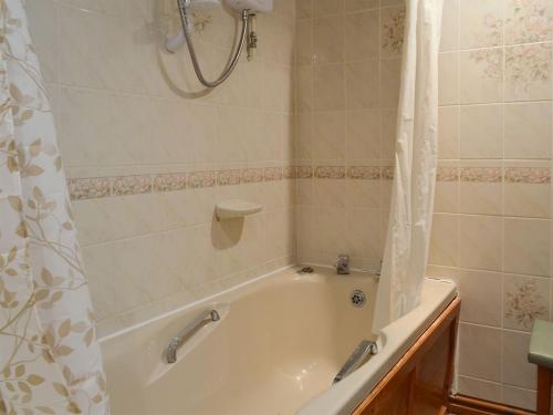 a bathroom with a bath tub with a shower curtain at Stable Cottage 8 - Ukc3747 in Bawdeswell