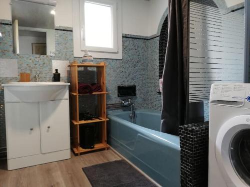 ein Badezimmer mit einer Badewanne, einem Waschbecken und einer Waschmaschine in der Unterkunft La maison du Lhéris in Bagnères-de-Bigorre