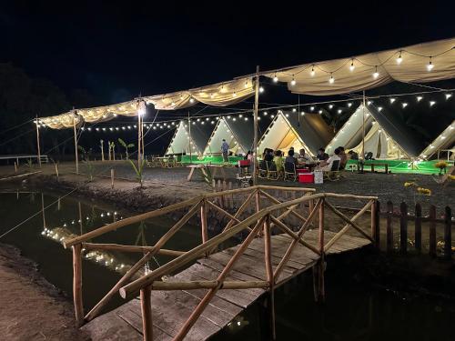 un groupe de personnes assis sous une tente la nuit dans l'établissement SAY Camp Forest, à Cần Giờ