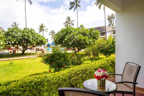 een tafel en stoelen met uitzicht op een park bij Nungwi Beach Resort by Turaco in Nungwi