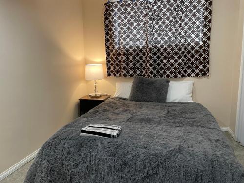 a bedroom with a bed with a blanket and a lamp at Super Luxury & Cozy Lower Level Apartment in NW Calgary, AB Close to Banff in Calgary