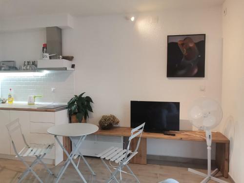 eine Küche mit einem Schreibtisch mit Fernseher und Stühlen in der Unterkunft Chicago Studio Apartment in Ohrid