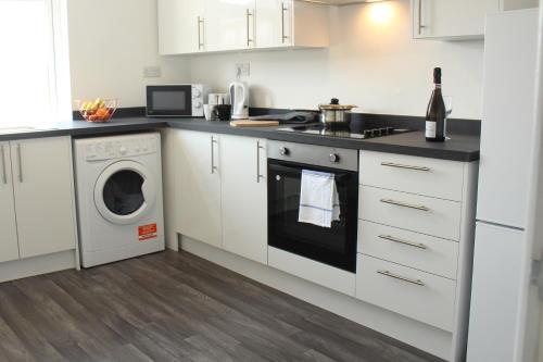 cocina con armarios blancos, lavadora y secadora en 1Bed Apartment in Heywood with Transport Links, en Heywood