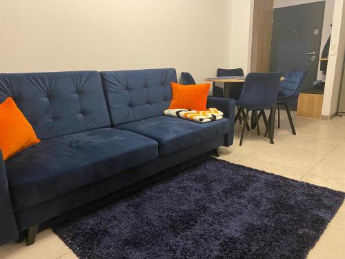a blue couch with orange pillows in a living room at Apartament Daszyńskiego in Suwałki