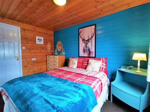 1 dormitorio azul con 1 cama y 1 silla azul en Glen Roe - 3 Bed Lodge on Friendly Farm Stay with Private Hot Tub, en New Cumnock