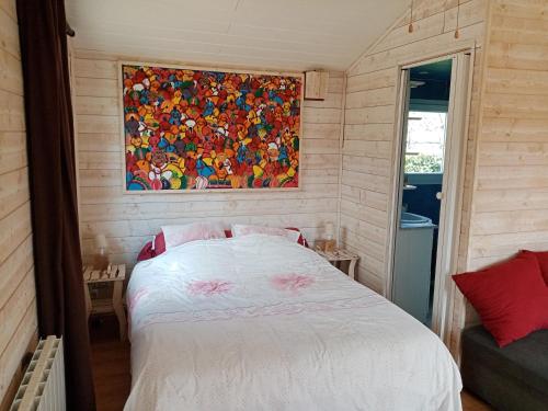 um quarto com uma cama branca e um quadro na parede em CHALET em La Guierche