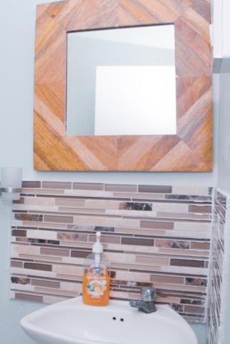 a bathroom with a mirror and a sink with a sink at Buttercup Cottage Apartments in Arnos Vale
