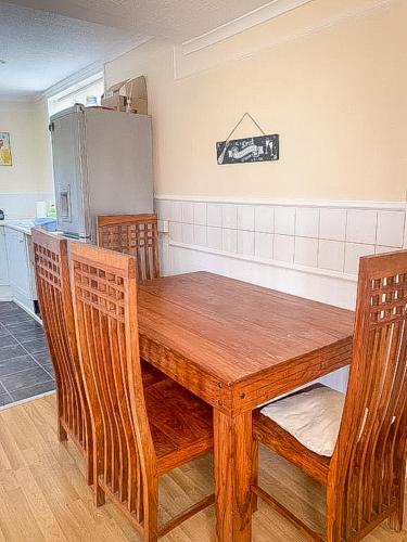 a kitchen with a wooden table with chairs and a refrigerator at Spacious 7 bed, Contractor Accommodation Stockton on tees in Stockton-on-Tees