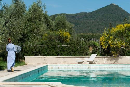 a woman standing next to a swimming pool at Agriturismo Tra gli Ulivi, Chiappini Winery in Bolgheri