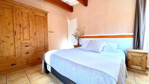 a bedroom with a bed and a wooden cabinet at Logis Hôtel Restaurant Le Domaine de l'Eau Vive in Largentière