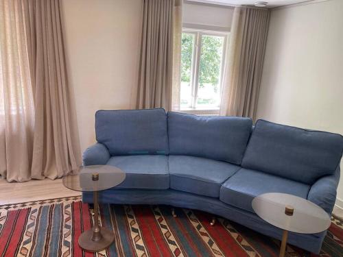 ein blaues Sofa im Wohnzimmer mit Fenster in der Unterkunft Slottsnära miljö. in Laholm