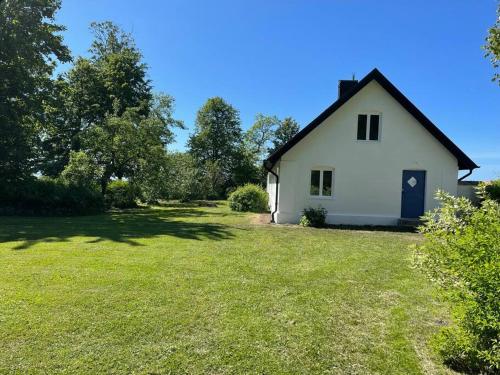 uma pequena casa branca com um grande quintal em Slottsnära miljö. em Laholm