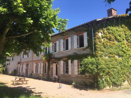 una casa vieja con una mesa de picnic delante de ella en Roulotte Un temps pour soi, en Bérat