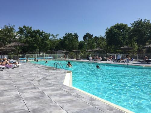 une grande piscine avec des gens dans l'eau dans l'établissement Le charme du Bassin d Arcachon en Mobil Home climatisé, à Arès