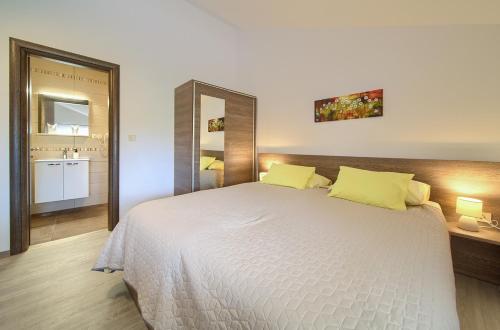 a bedroom with a large white bed with yellow pillows at Apartmani DAL in Malinska
