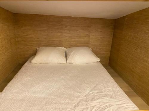 - un lit avec 2 oreillers blancs dans l'établissement Superbe et accuiellent appartement, au Kremlin-Bicêtre