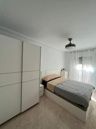Dormitorio blanco con cama y armario en Ático duplex con Vista Mar y Terraza Privada a 200m de la playa hasta 6 personas, en Garrucha