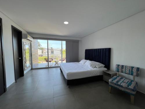 - une chambre avec un lit, une fenêtre et une chaise dans l'établissement Hotel Emerawaa Centro Historico, à Ríohacha