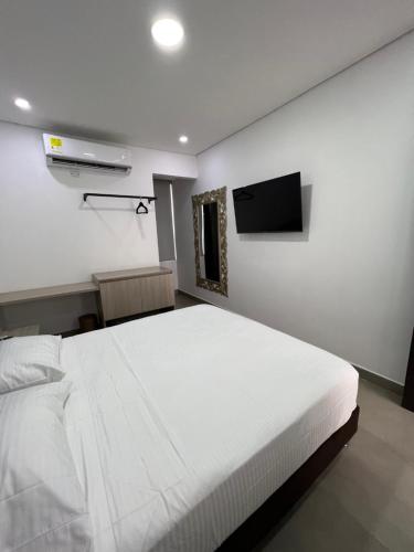 a bedroom with a white bed and a flat screen tv at Hotel Emerawaa Centro Historico in Ríohacha