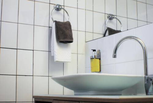 a white sink in a bathroom with white tiles at Sunnybank Star Hotel in Brisbane