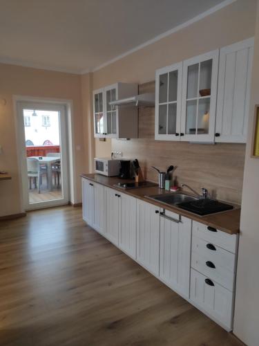 a kitchen with white cabinets and a wooden floor at Apartmány Greg in České Budějovice