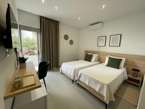 Habitación de hotel con 2 camas y escritorio en Helen's Seaside Resort, en Sarandë