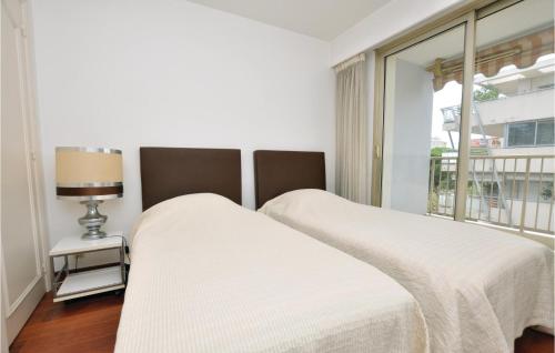 カンヌにあるCozy Apartment In Cannes With Wifiの白いベッドルーム(ベッド2台、窓付)