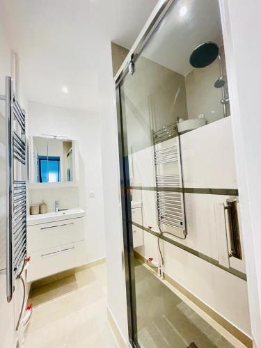 une salle de bain blanche avec un lavabo et un miroir dans l'établissement Charmant T3, à 15 minutes de Paris, à Argenteuil