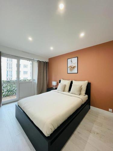 une chambre avec un grand lit avec une grande fenêtre dans l'établissement Charmant T3, à 15 minutes de Paris, à Argenteuil