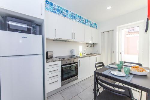a kitchen with a table and a white refrigerator at Vasco Da Gama Apartments in Lagos
