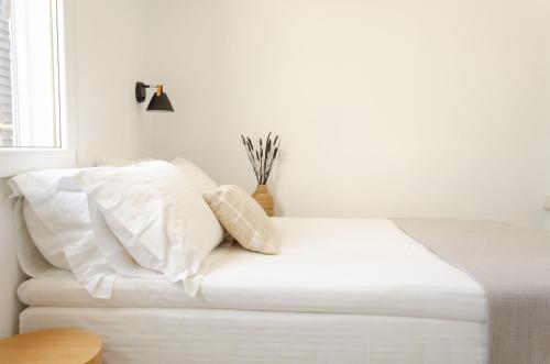 a bed with white sheets and pillows in a room at Eleana Hotel in Tinos Town